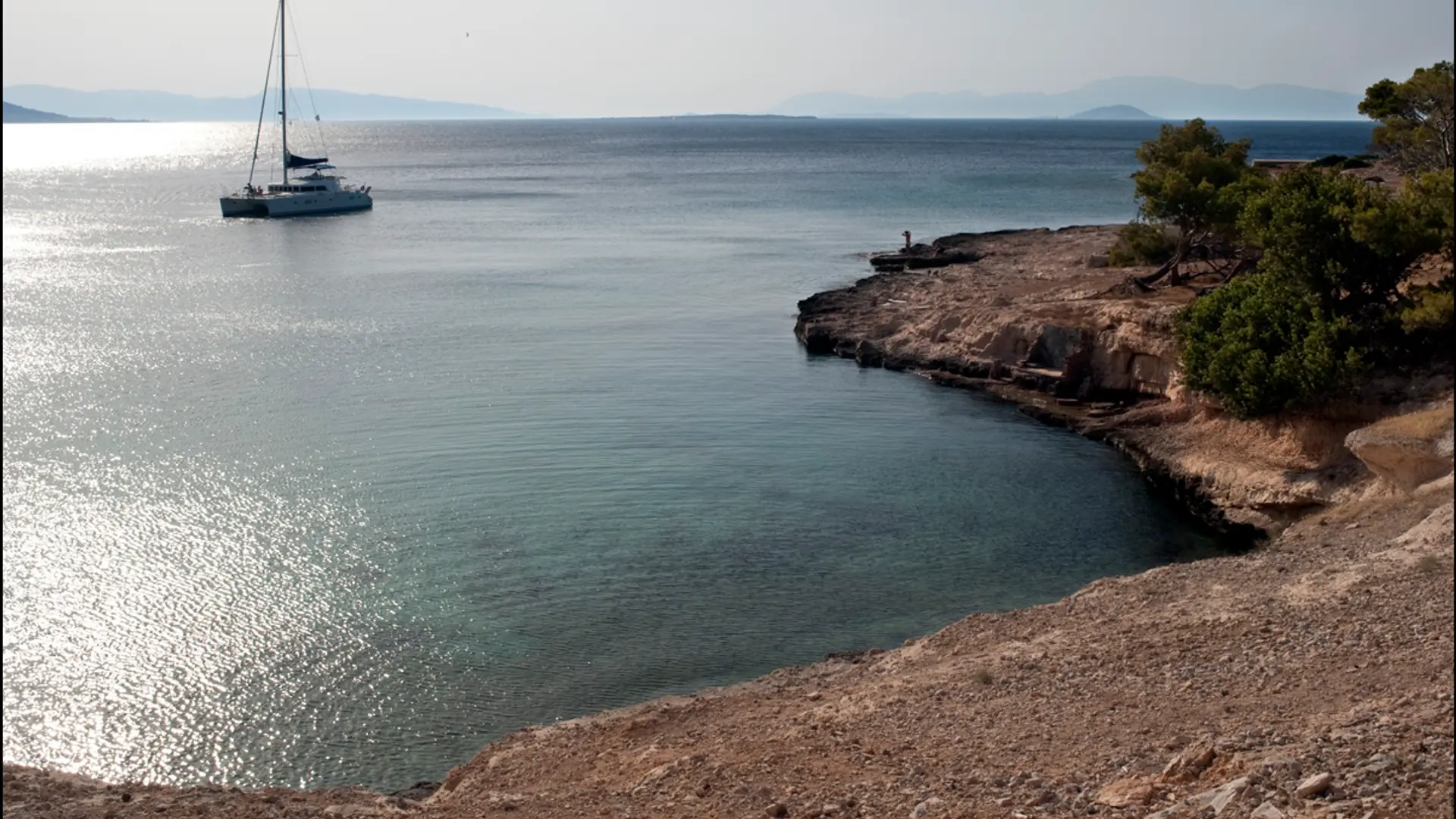 A secluded rocky cove with a sailing yacht off Moni Island